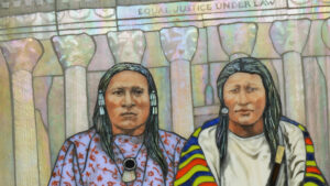 A piece of art featuring two native american figures standing in front of a shimmery background.