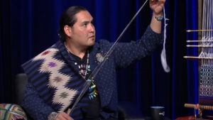 Navajo weaver Venancio Aragon holding up a piece of yarn.