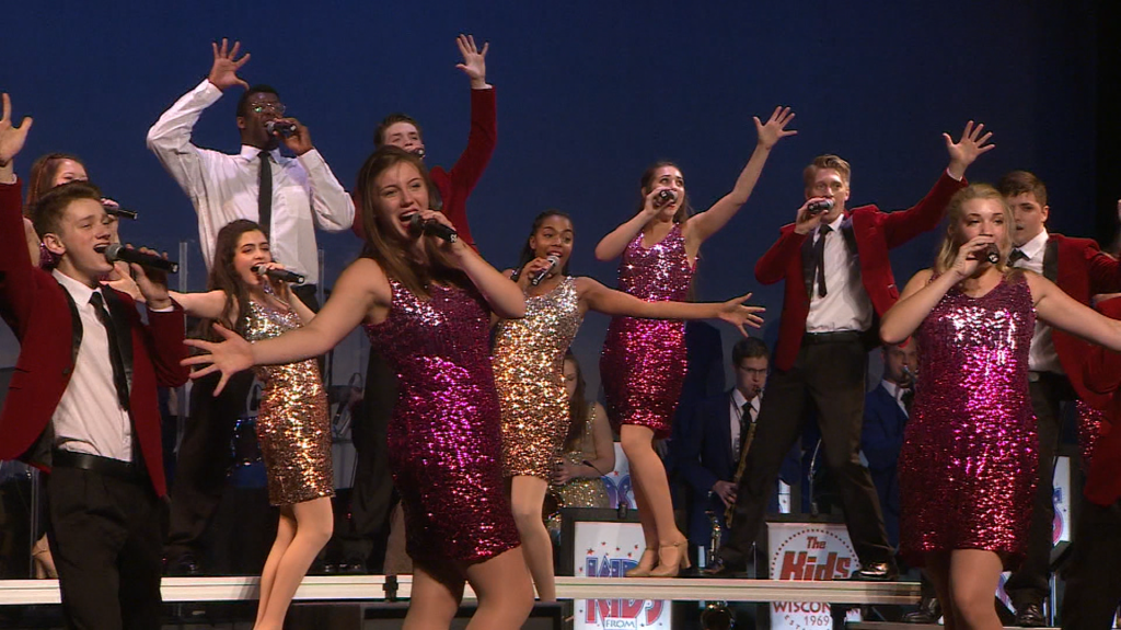 A performance of "Kids from Wisconsin" performed by young indivduals singing in fancy outfits.