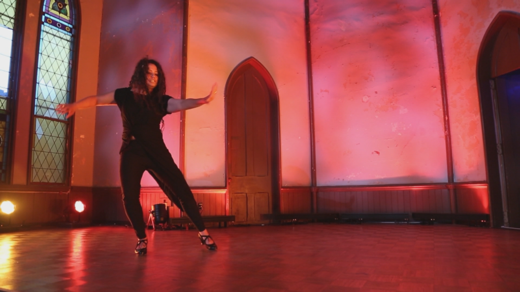 A person dancing flamenco in a red lit room.