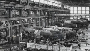 A black and white photo of a factory building train cars.