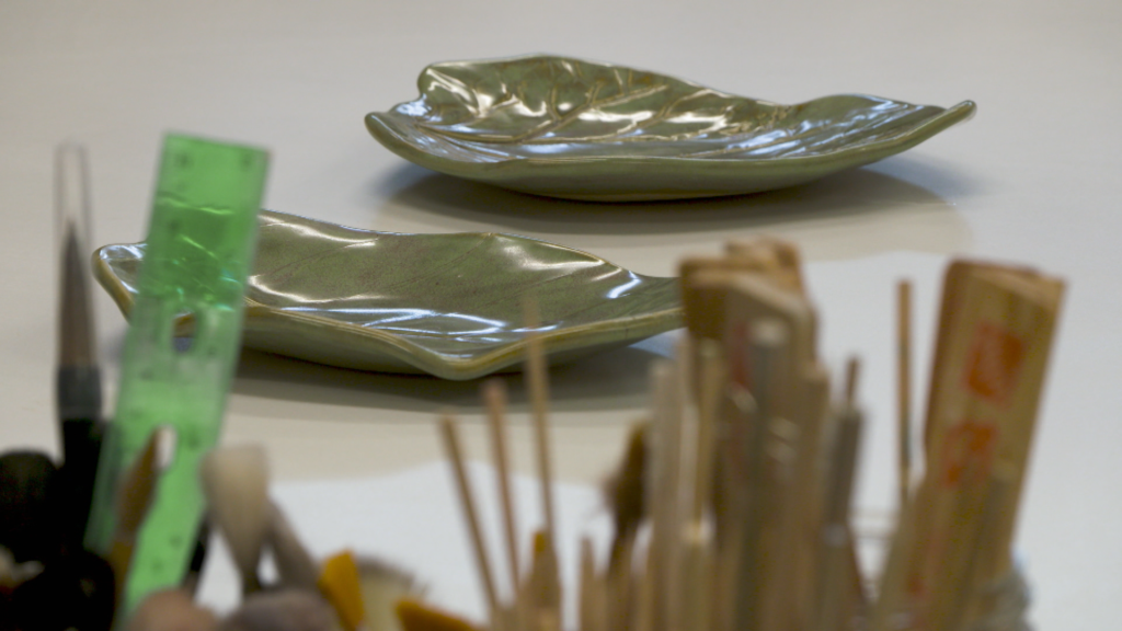 Troy Drake's pottery of two green leaves with the tools they use in the foreground.