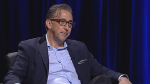 A man in glasses sitting in a chair.