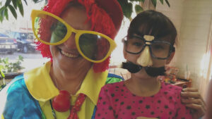 A woman dressed as a clown with a little girl.