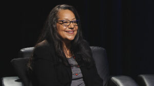 A woman with glasses sitting in a chair.