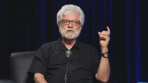 A man with a beard and glasses sitting in a chair.