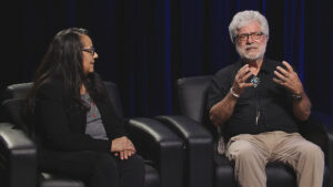 A man and woman sitting in chairs talking to each other.