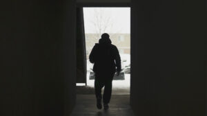 A silhouette of a person walking down a hallway.