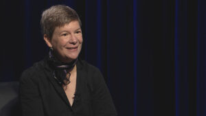 A woman in a black shirt sitting in a chair.