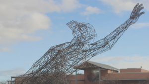 A statue of a man with his arms outstretched in front of a building.