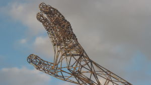 A sculpture of a hand with a cloudy sky.