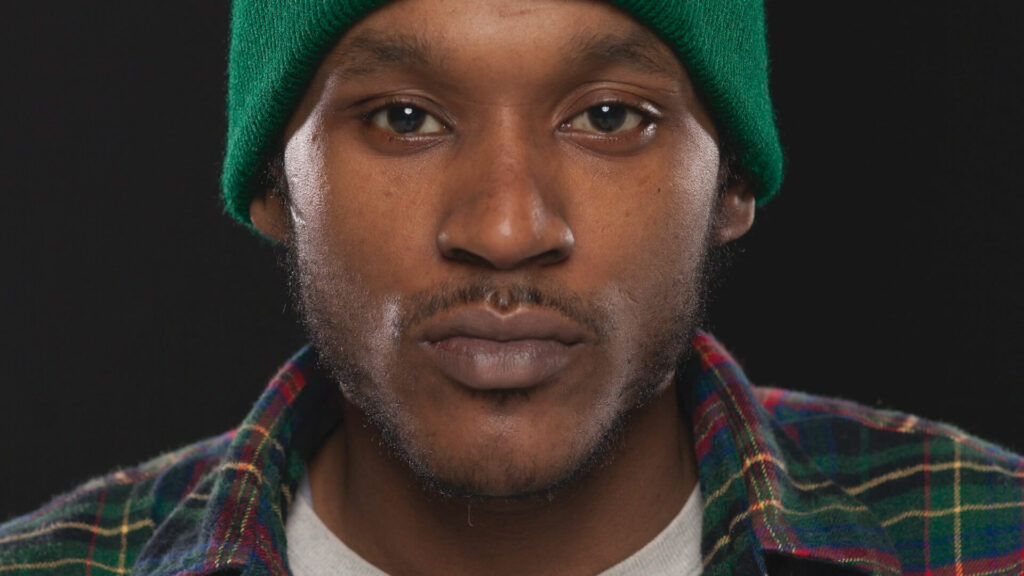 A man wearing a green beanie and plaid shirt.