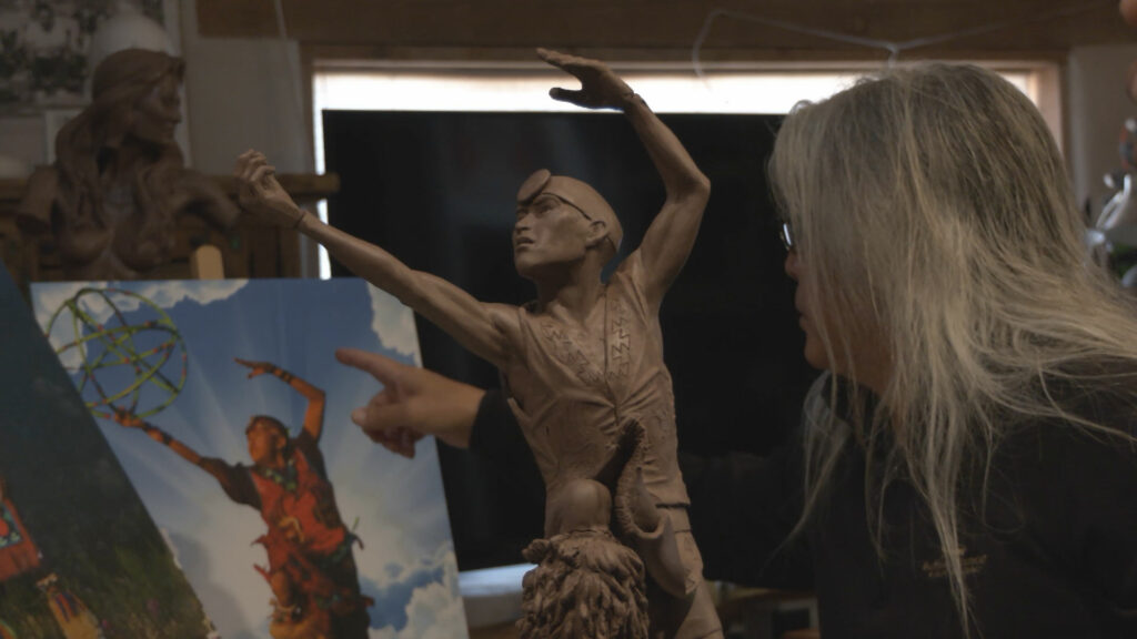 A woman is pointing to a statue in a studio.