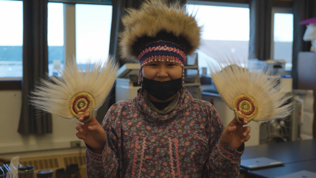 A woman holding two feathers in her hands.