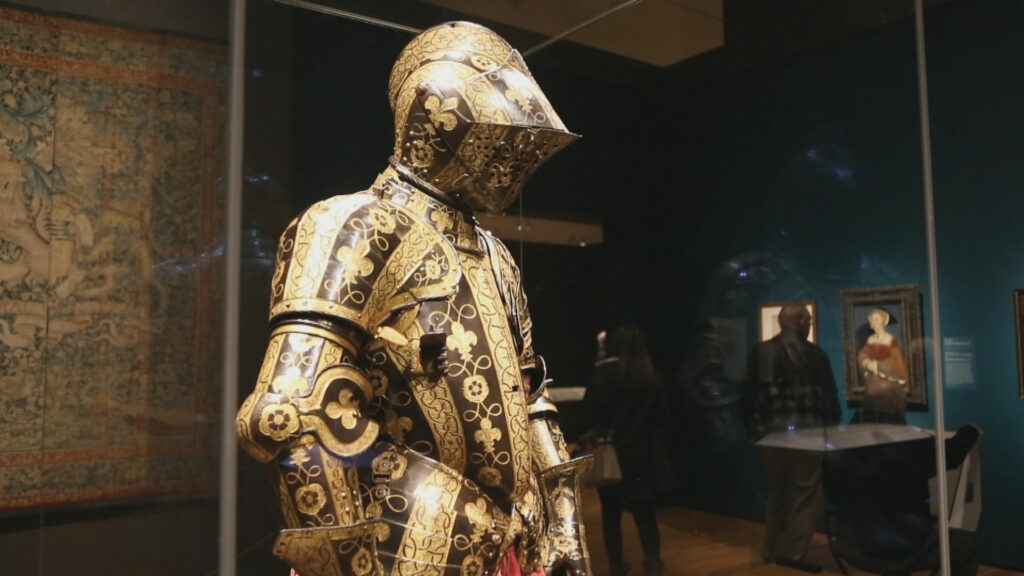 A gold armor is on display in a museum.