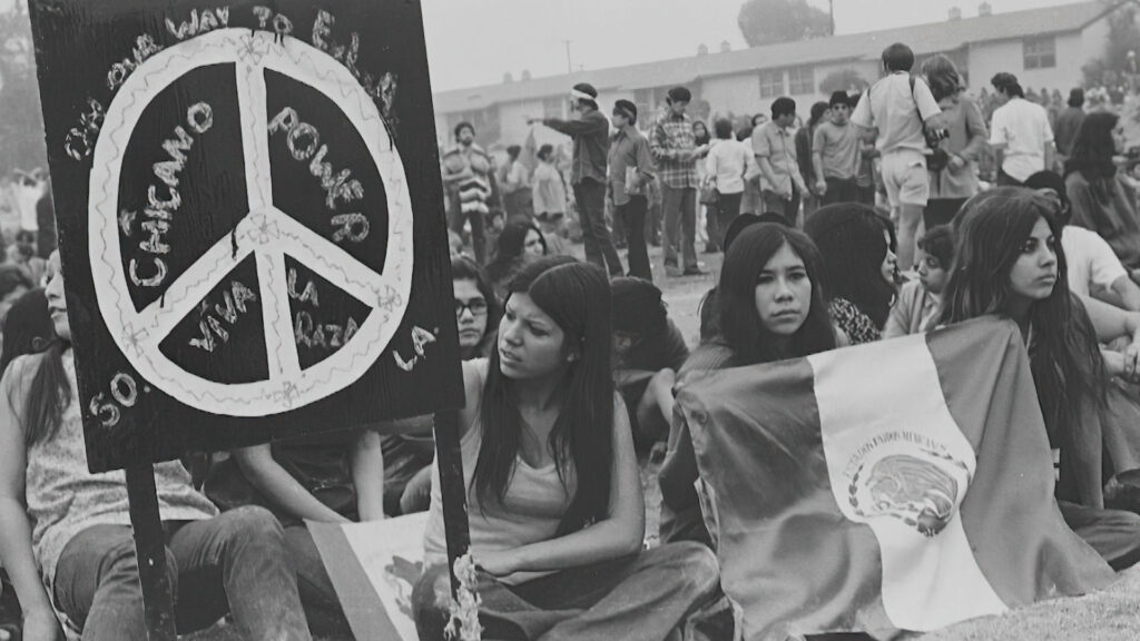 A black and white photo of a group of people holding peace signs.