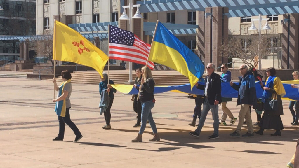 A group of people walking with flags in front of a building.