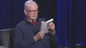 An older man sitting in a chair reading a book.