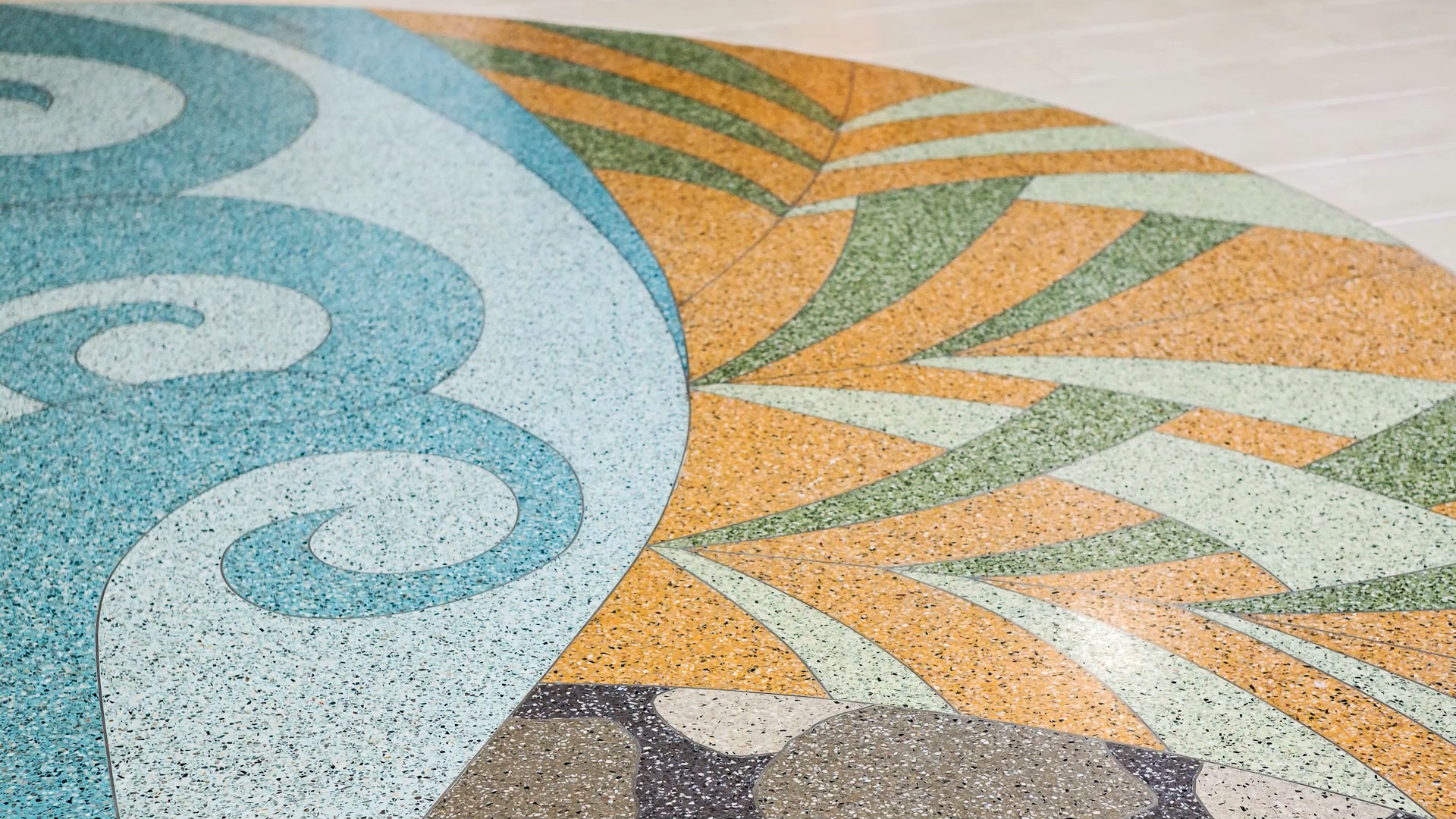 A terrazzo floor with geometric and swirling patterns in shades of blue, brown, orange, green, and beige.