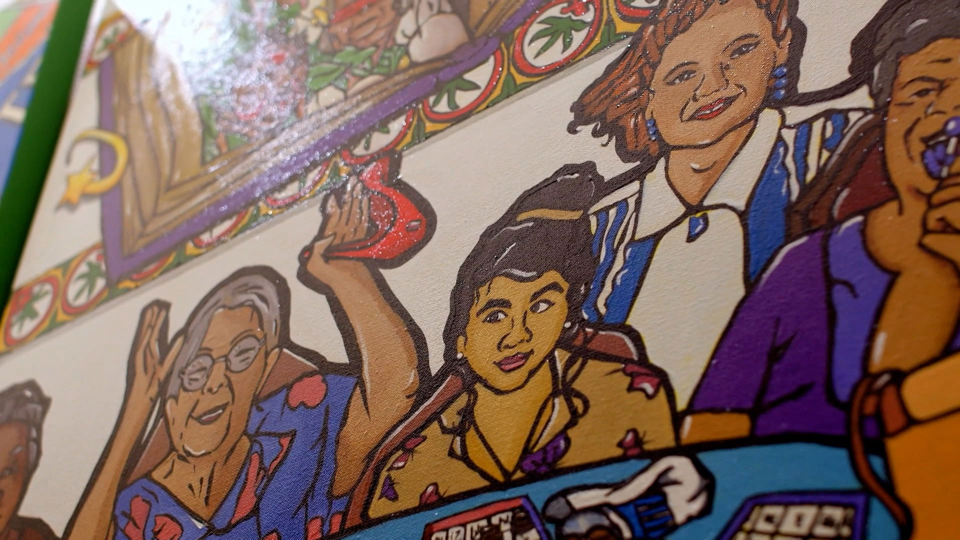 Colorful mural depicting three women sitting at a table playing a game, with one woman raising her hand and vibrant patterns in the background.