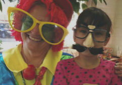 A woman dressed as a clown with a little girl.