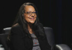 A woman with glasses sitting in a chair.
