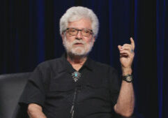 A man with a beard and glasses sitting in a chair.