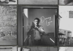 A black and white photograph of a man taking a picture.
