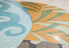 A terrazzo floor with geometric and swirling patterns in shades of blue, brown, orange, green, and beige.