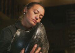 Rose Simpson looking up close on a clay piece of pottery.