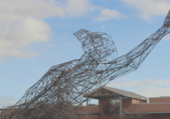 A statue of a man with his arms outstretched in front of a building.