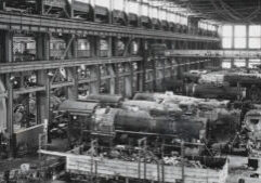 A black and white photo of a factory building train cars.