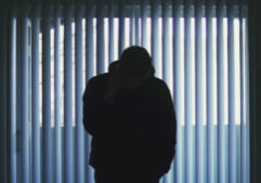 A silhouette of a person standing in front of a window.