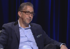 A man in glasses sitting in a chair.