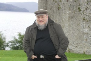 A man with a beard standing in front of a stone wall.