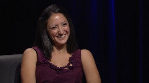 A woman smiling in a purple shirt.