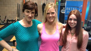 Three women posing for a picture in a gym.
