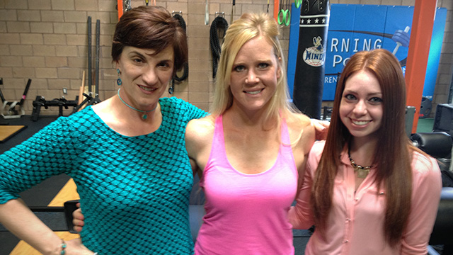 Three women posing for a picture in a gym.