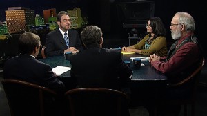A group of people sitting around a table in a television studio.