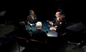 A group of people sitting around a table in a dark room.