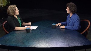 Two women sitting at a table talking to each other.