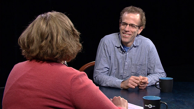 A man and woman sitting at a table talking.