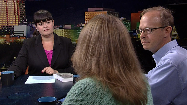 Three people sitting at a table in front of a city.