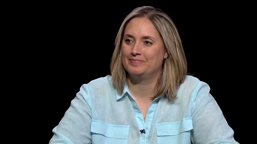 A woman in a blue shirt sitting at a table.