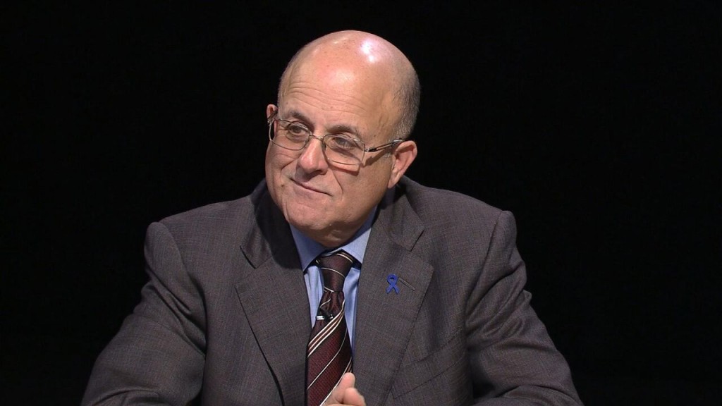 A bald man in a suit and tie sitting at a table.