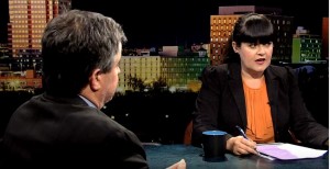 A man and woman sitting at a table in front of a city.