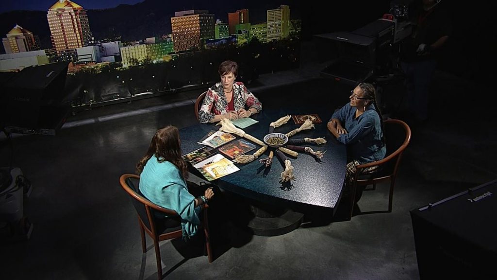 Three women sitting around a table in a studio.