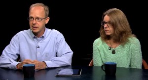 A man and woman sitting at a table with a cup of coffee.