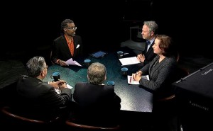 A group of people sitting around a table in a dark room.