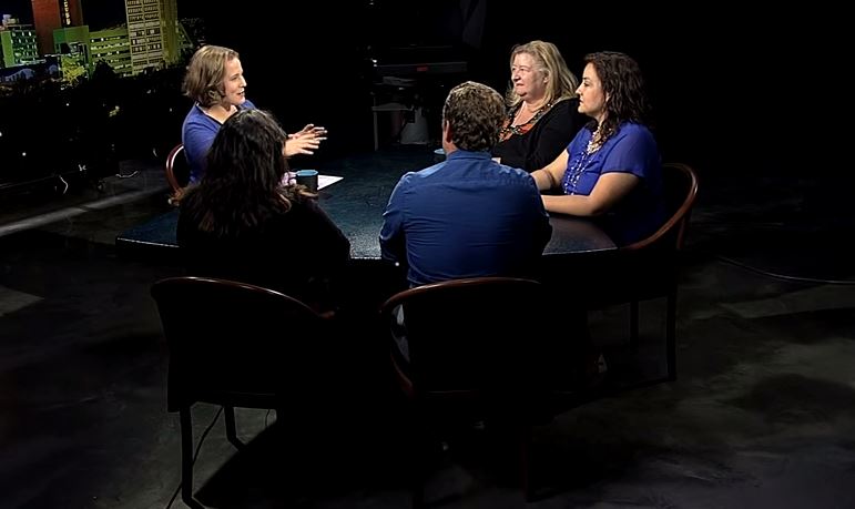 A group of people sitting around a table in a dark room.